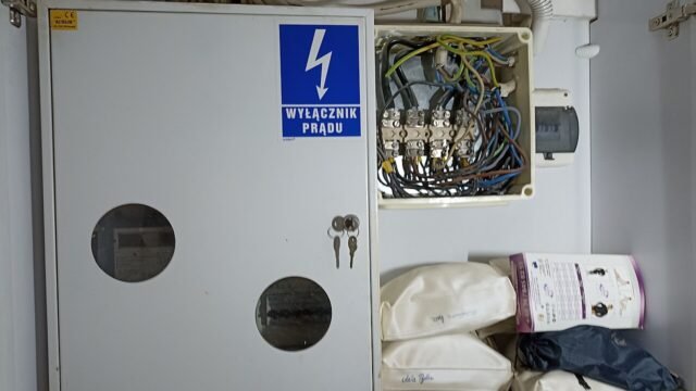 Rozdzielnica elektryczna z tabliczką „Wyłącznik prądu” w lokalu użytkowym w Poznaniu